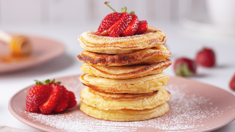 Fluffy pancakes topped with strawberries and powdered sugar