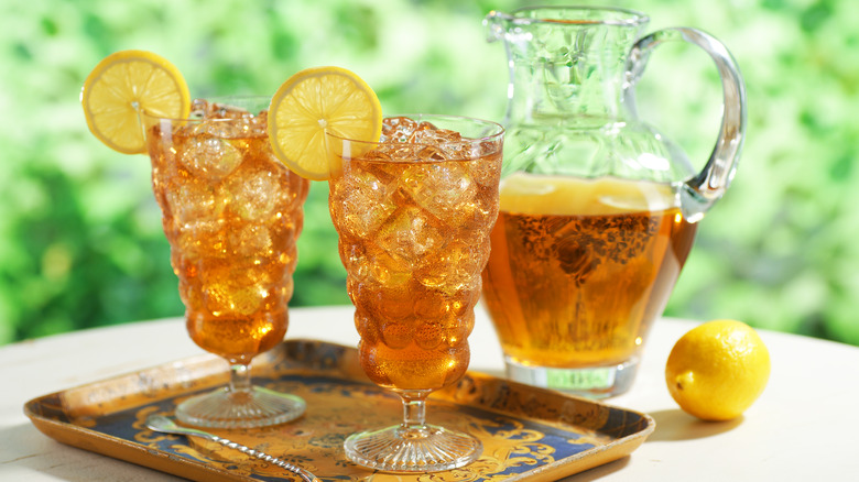 Two glasses of iced tea beside a pitcher